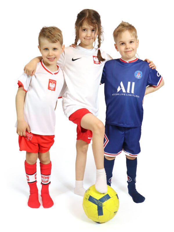 Dziewczynka i dwóch chłopców ubranych w kompletne dziecięce stroje piłkarskie