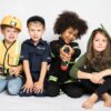 Grupa dzieci w strojach budowniczego, policjanta, strażaka i dinozaura